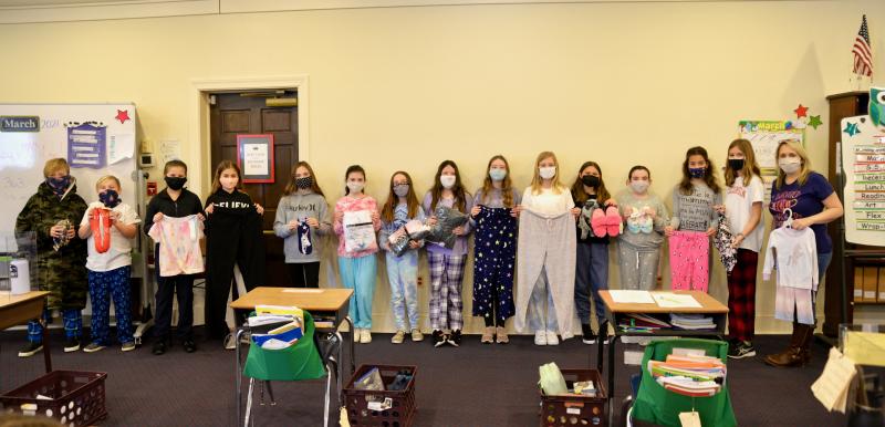 Fifth-graders celebrated by coming to school in their pajamas and donating 100 new comfort wear items to those in need at Diakonia. Shown with some of the donated items including new pajamas, slippers, robes, socks, sweat pants and T-shirts are (l-r) Luke Mize, John Lynch, Eva Tekmen, Ruya Kucuk, Ryan Shipp, Gracie Holloway, Arianna Dorfler, Emma Brooks, Sarah Williams, Harper Hertrich, Vivien Ruggerio, Nora Gorfinkel, Elena Gjoni, Samantha Kuon and teacher Lisa Rill.